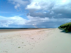 A white sandy beach, blue sky and a rainbow
